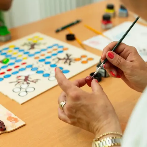 Hände malen mit einem feinen Pinsel ein Spielbrett aus